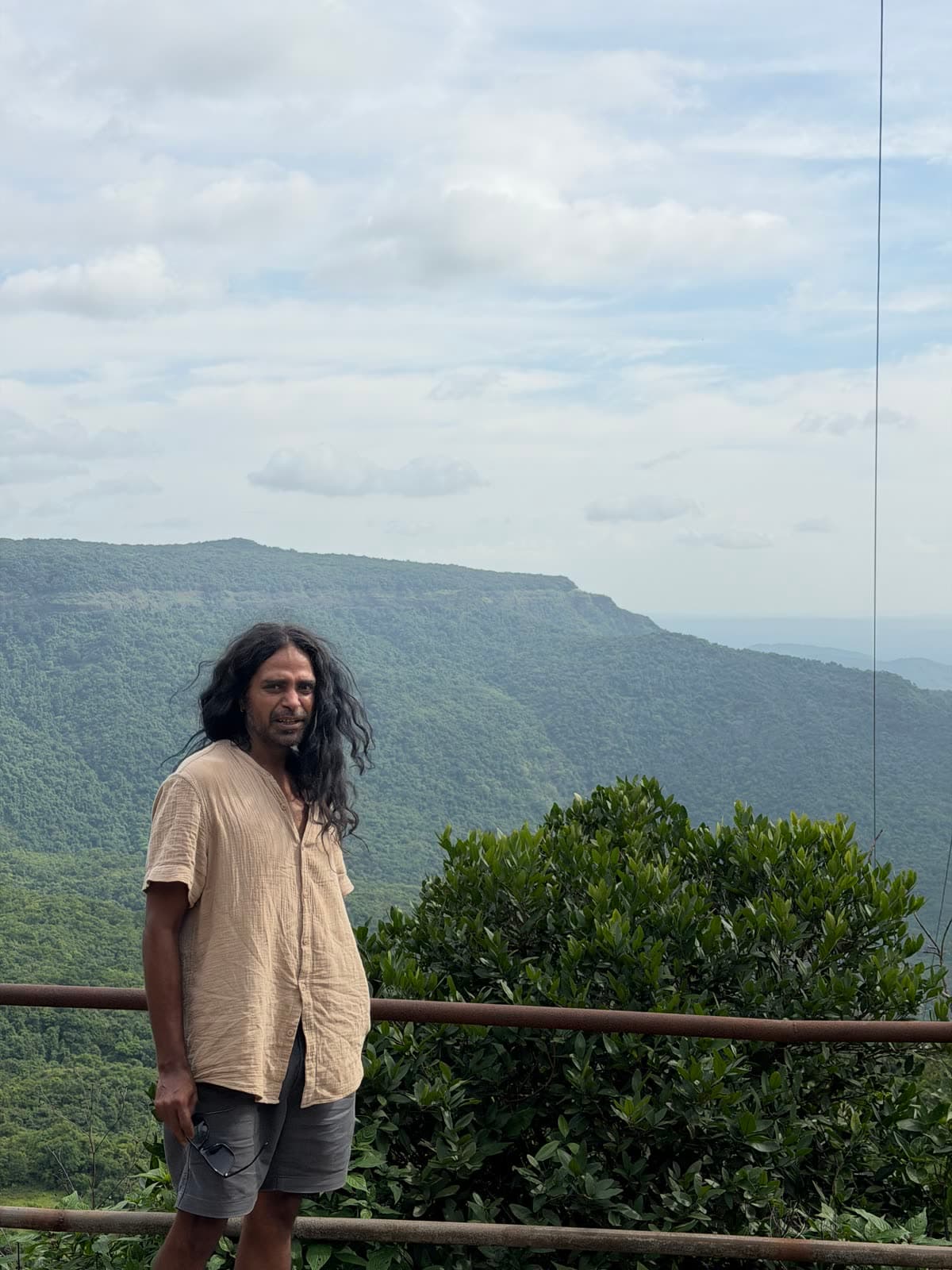 Sharvil Gandhi standing at a lookout above forested hills